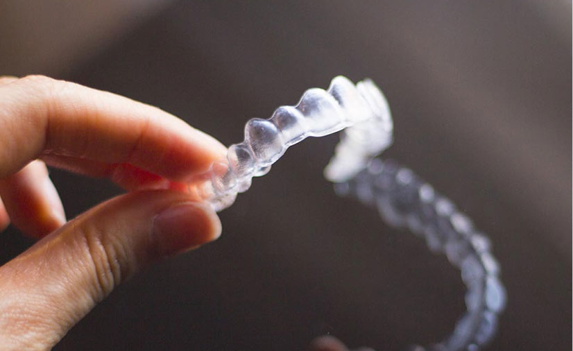 Hand Holding Invisalign Clear Dental Aligners